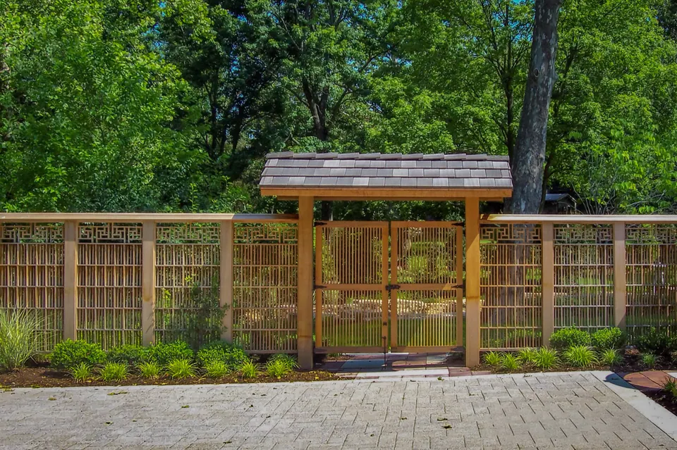 Wood garden fence and double gate with a small roof over a paver courtyard